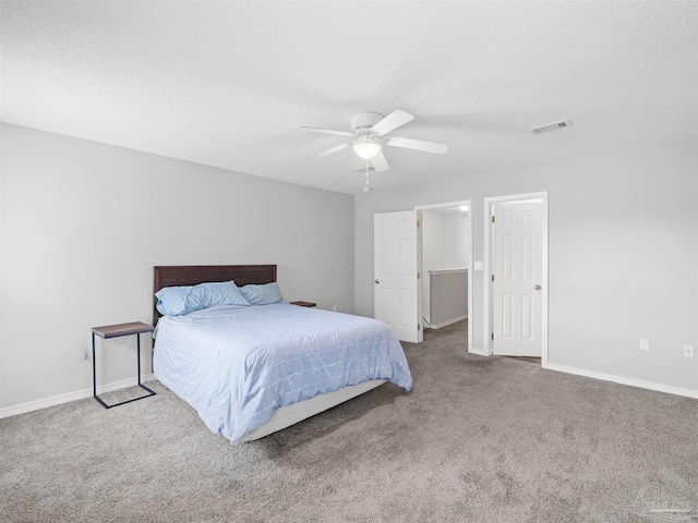 carpeted bedroom with visible vents, a textured ceiling, baseboards, and a ceiling fan