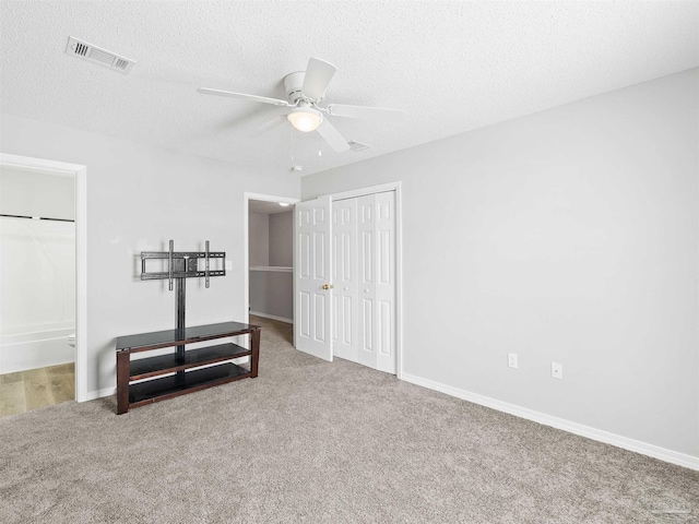 interior space with carpet, baseboards, visible vents, ceiling fan, and a textured ceiling