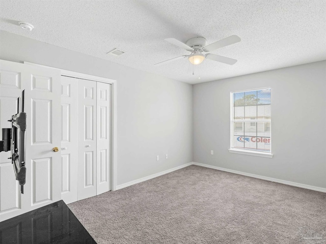 unfurnished bedroom featuring a closet, carpet flooring, a textured ceiling, and baseboards