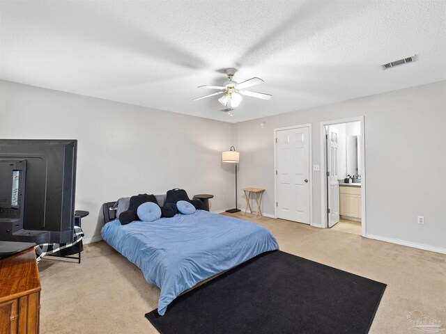 bedroom with visible vents, baseboards, light colored carpet, and a textured ceiling