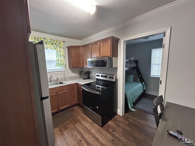 kitchen with dark wood-type flooring, sink, a textured ceiling, ornamental molding, and appliances with stainless steel finishes