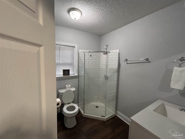 bathroom with hardwood / wood-style flooring, a shower with door, a textured ceiling, and toilet