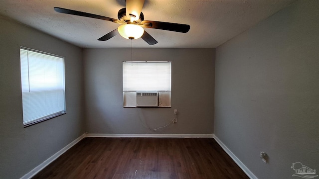 spare room featuring dark wood-type flooring, cooling unit, a healthy amount of sunlight, and ceiling fan