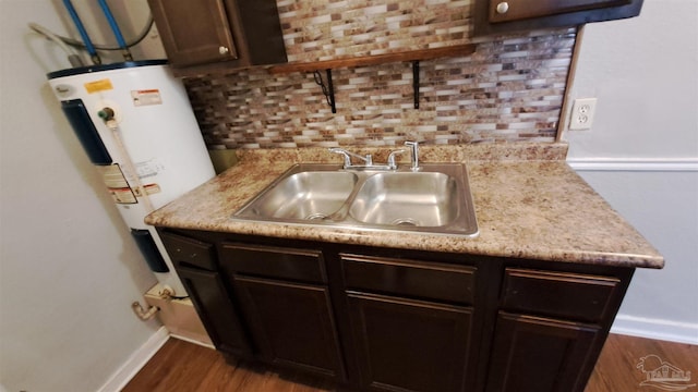 kitchen with dark wood-type flooring, sink, decorative backsplash, water heater, and dark brown cabinets