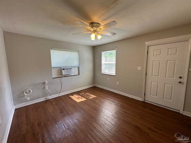 empty room featuring a textured ceiling, dark hardwood / wood-style floors, cooling unit, and ceiling fan