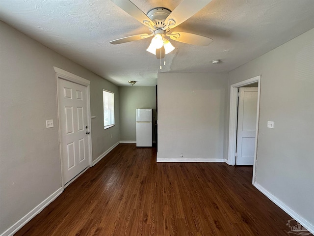 empty room with ceiling fan, dark hardwood / wood-style flooring, and a textured ceiling