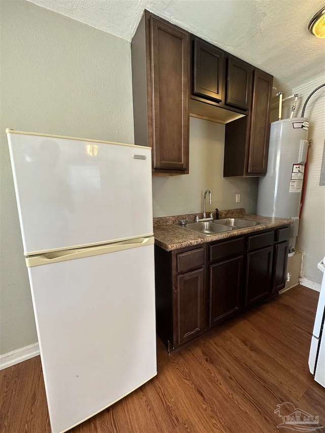 kitchen with a textured ceiling, white refrigerator, dark hardwood / wood-style floors, and sink