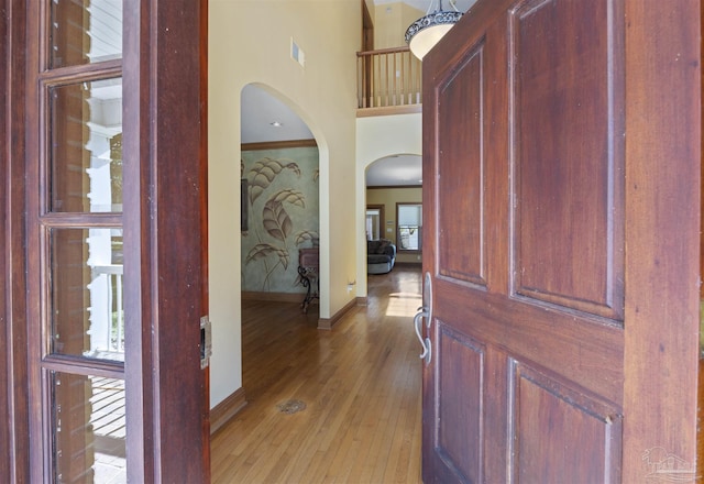 entryway featuring a towering ceiling, crown molding, and light hardwood / wood-style floors