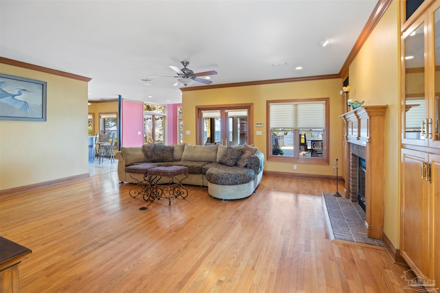 living room featuring ornamental molding, a fireplace, light hardwood / wood-style floors, and ceiling fan