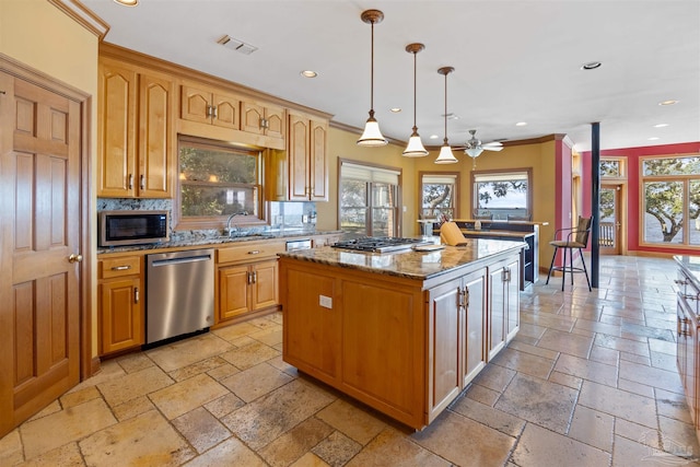 kitchen with light stone counters, appliances with stainless steel finishes, a center island, and plenty of natural light