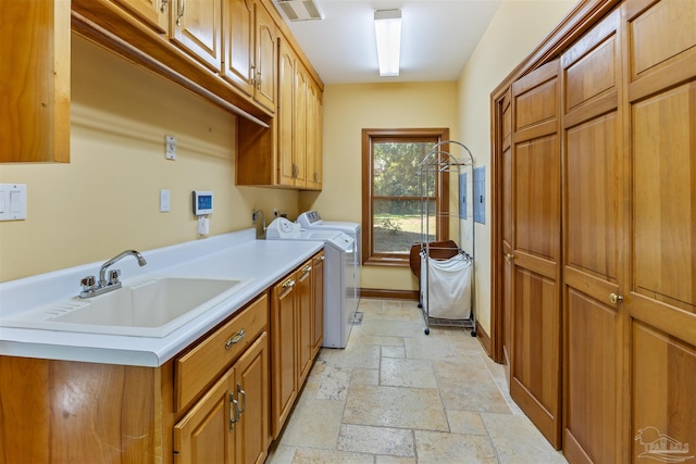 clothes washing area featuring cabinets, sink, and washer and clothes dryer