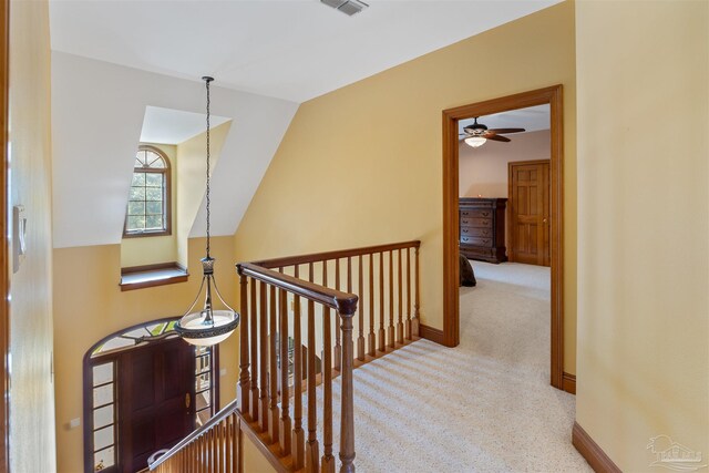 hallway with vaulted ceiling and light carpet