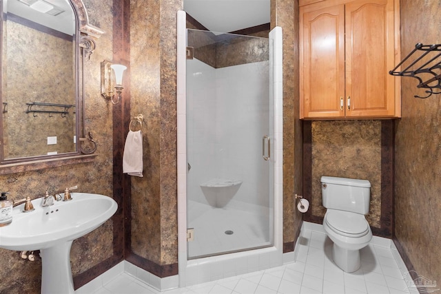 bathroom with a shower with door, toilet, and tile patterned floors