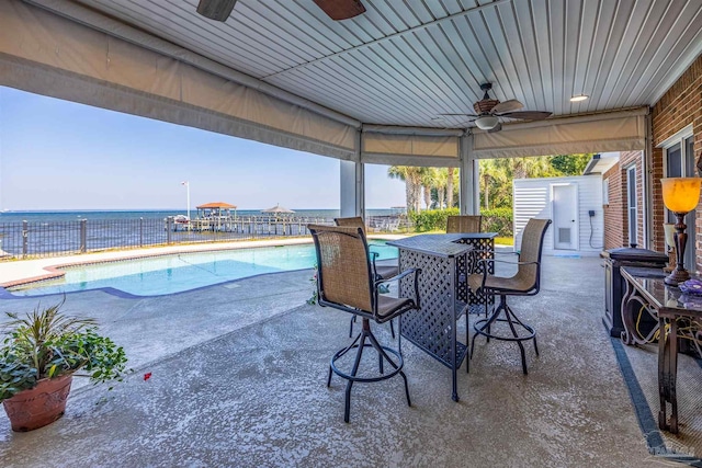 view of patio / terrace with a water view, ceiling fan, and a fenced in pool