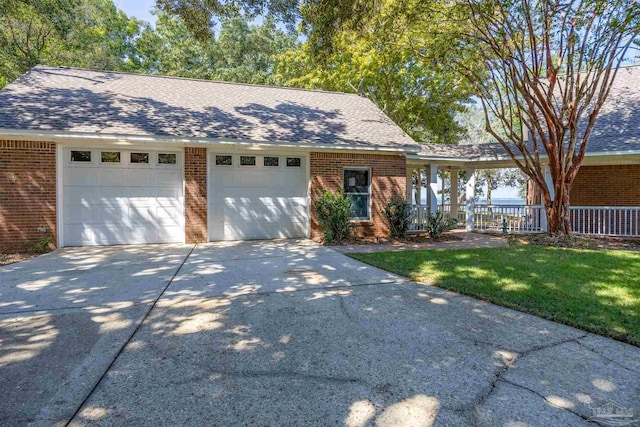 view of front of home featuring a porch, a front lawn, and a garage