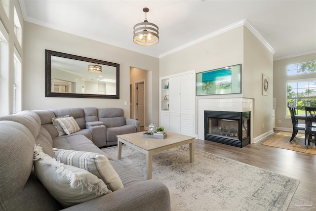 4282 Walden Way, Gulf Breeze, FL 32563 - living room featuring crown molding, wood finished floors, a chandelier, baseboards, and a tiled fireplace