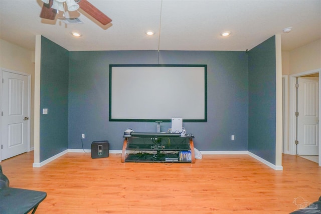 cinema room with hardwood / wood-style floors and ceiling fan