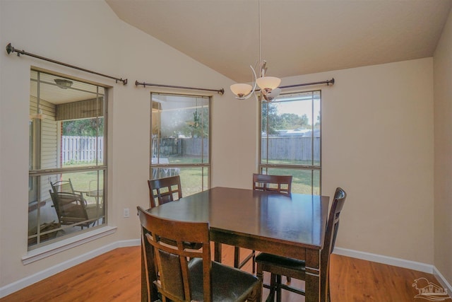 dining area with light wood-type flooring, lofted ceiling, and a chandelier