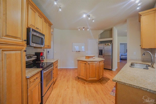 kitchen with light wood-type flooring, a center island, appliances with stainless steel finishes, and sink