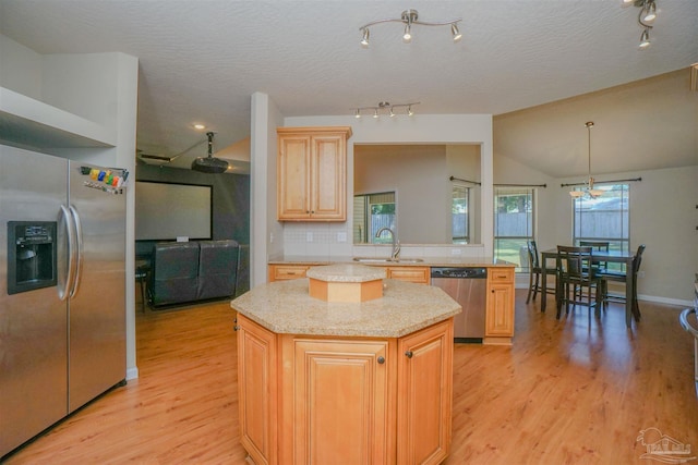 kitchen featuring pendant lighting, lofted ceiling, stainless steel appliances, a center island, and light wood-type flooring