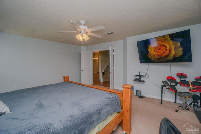 carpeted bedroom featuring ceiling fan and a textured ceiling