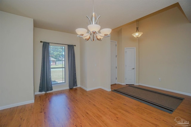 empty room with a notable chandelier and hardwood / wood-style floors