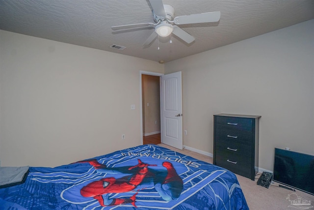 carpeted bedroom featuring ceiling fan and a textured ceiling