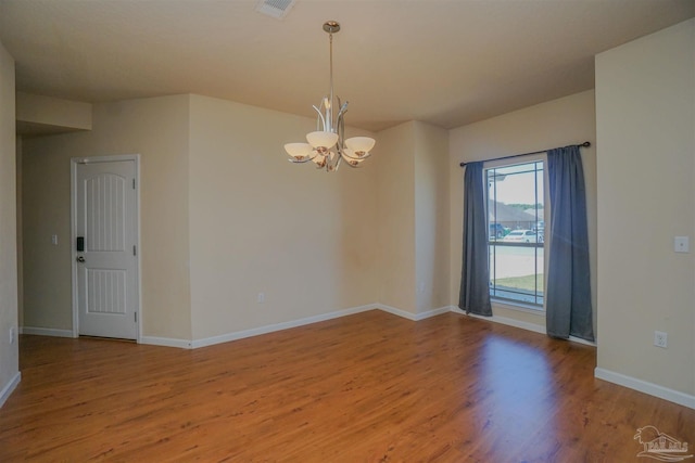 unfurnished room with an inviting chandelier and hardwood / wood-style floors