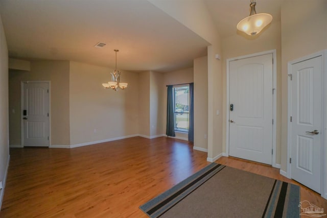 foyer entrance featuring vaulted ceiling, hardwood / wood-style floors, and a chandelier