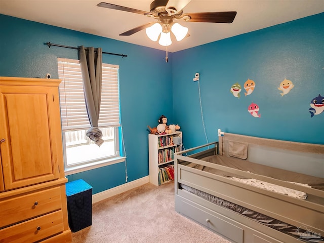 bedroom featuring light colored carpet, baseboards, and ceiling fan