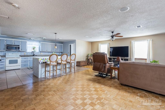 living room with a textured ceiling, light parquet flooring, and plenty of natural light