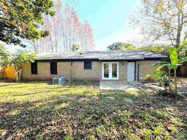 back of property featuring french doors, central AC unit, and a lawn