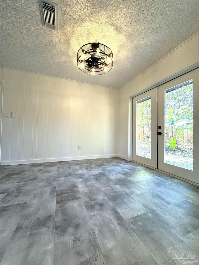 unfurnished dining area with a textured ceiling and french doors