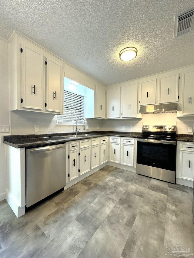 kitchen with a textured ceiling, stainless steel appliances, white cabinetry, and sink