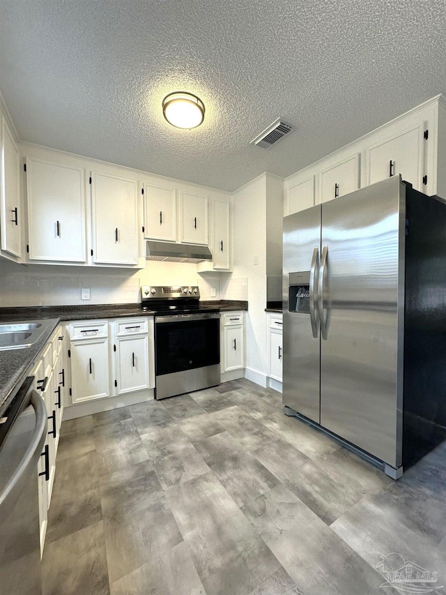 kitchen featuring white cabinets, stainless steel appliances, and a textured ceiling