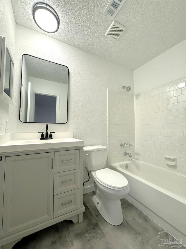 full bathroom featuring vanity, toilet, a textured ceiling, and tiled shower / bath