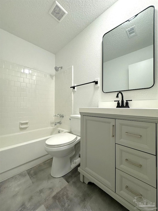 full bathroom featuring tiled shower / bath, vanity, a textured ceiling, and toilet