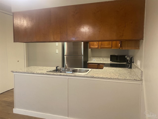 kitchen featuring stainless steel refrigerator, dark wood-type flooring, sink, and light stone counters