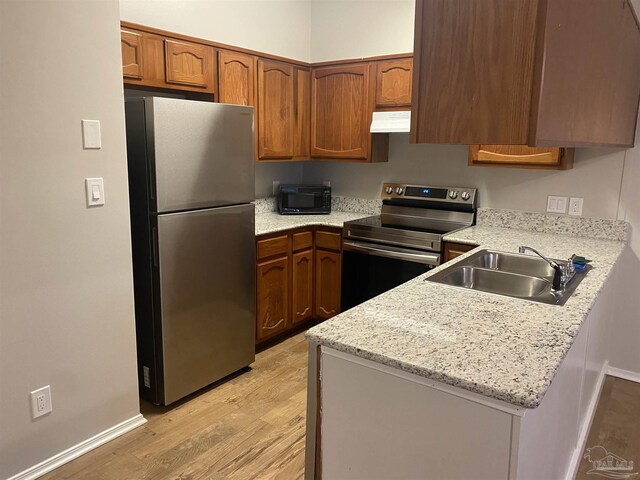 kitchen featuring sink, light hardwood / wood-style flooring, kitchen peninsula, stainless steel appliances, and light stone countertops