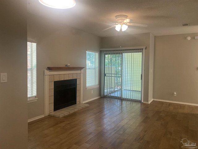 unfurnished living room featuring hardwood / wood-style floors, a textured ceiling, a tile fireplace, and ceiling fan