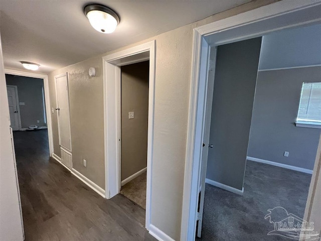 corridor with dark wood finished floors and baseboards