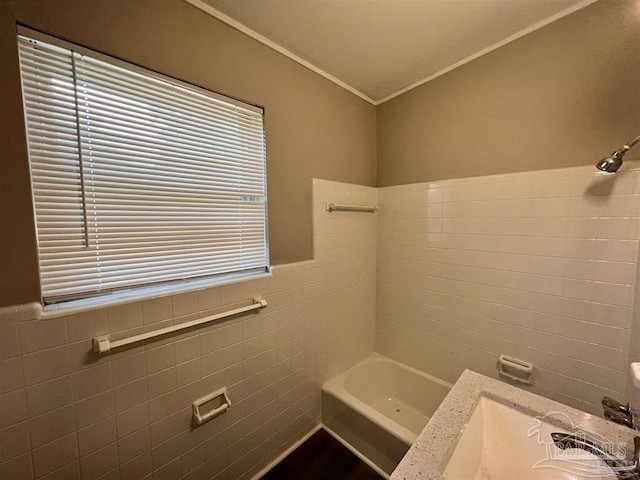 full bath with ornamental molding, wainscoting, a sink, and tile walls