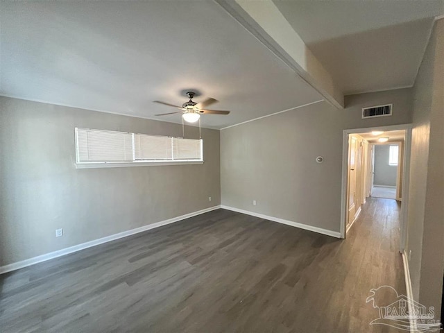 empty room with dark wood-type flooring, beam ceiling, visible vents, and baseboards