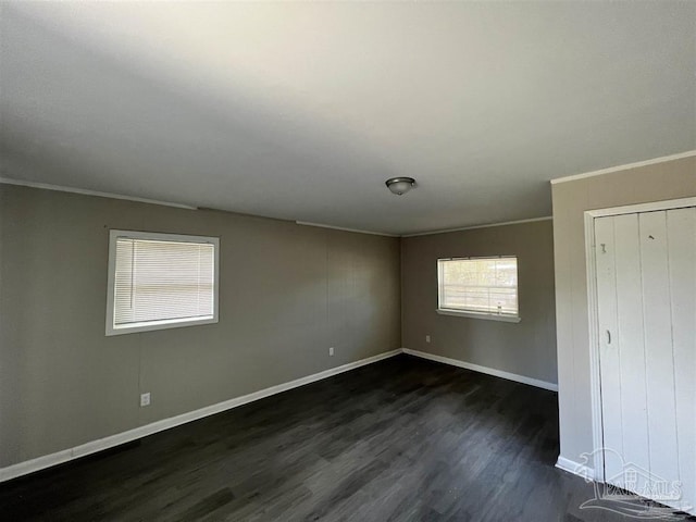 unfurnished bedroom with dark wood-style floors, a closet, baseboards, and crown molding