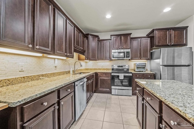 kitchen featuring appliances with stainless steel finishes, sink, backsplash, light tile patterned floors, and light stone counters