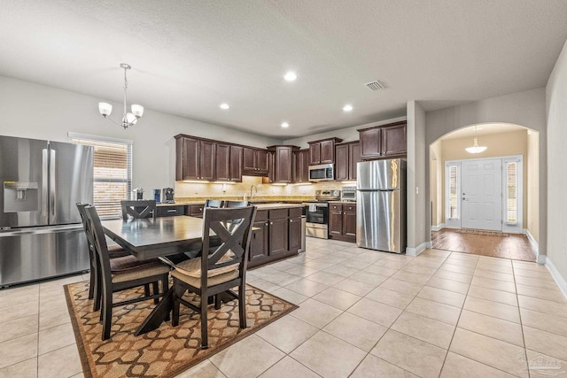 dining area with sink, light tile patterned floors, a notable chandelier, and a textured ceiling