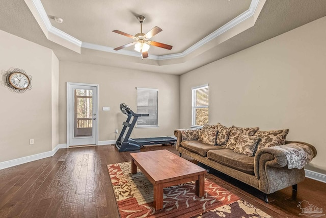 living room with ornamental molding, plenty of natural light, dark hardwood / wood-style flooring, and a tray ceiling