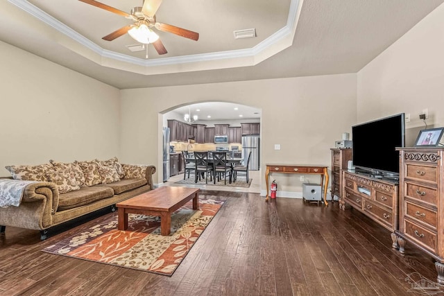 living room featuring ceiling fan, ornamental molding, dark hardwood / wood-style flooring, and a raised ceiling