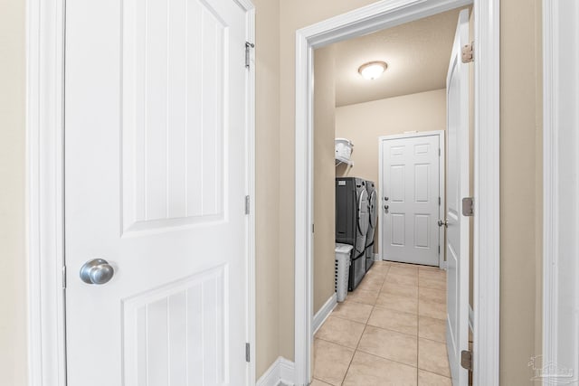 hallway with light tile patterned floors and washing machine and dryer