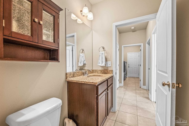 bathroom featuring tile patterned floors, toilet, washer / dryer, and vanity